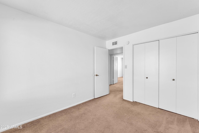 unfurnished bedroom with light colored carpet and a closet