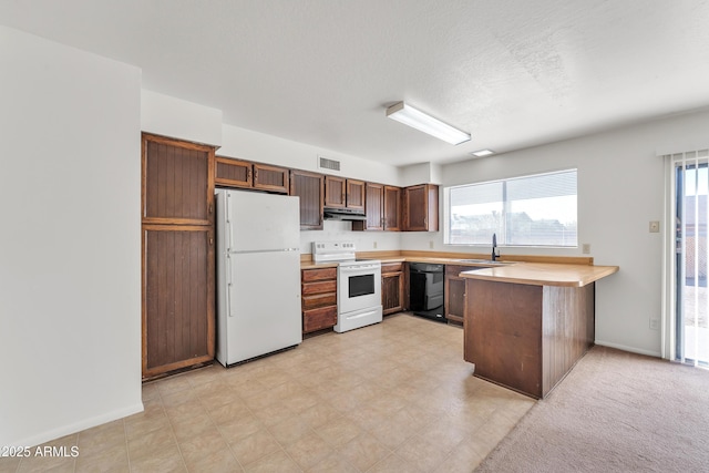 kitchen with plenty of natural light, a textured ceiling, white appliances, and kitchen peninsula