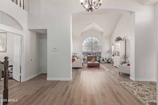 entrance foyer with an inviting chandelier, a towering ceiling, and light wood-type flooring