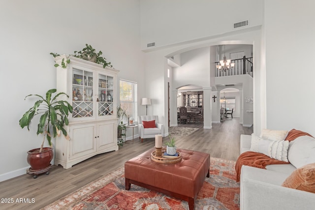 living room with a high ceiling, a chandelier, and light hardwood / wood-style flooring