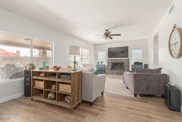 living room with ceiling fan, a tile fireplace, and light hardwood / wood-style flooring