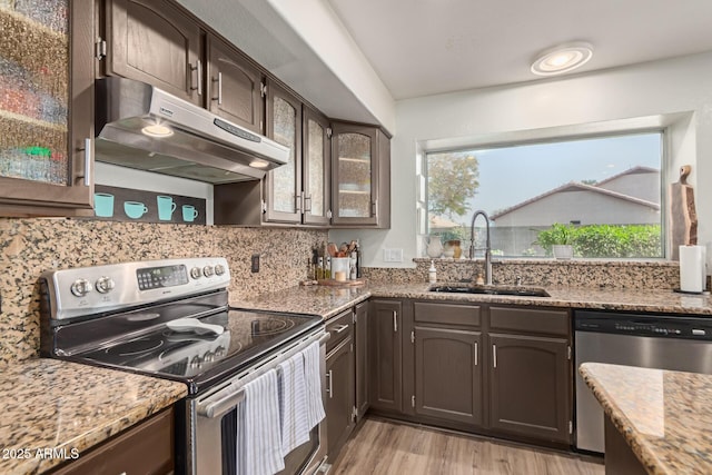 kitchen featuring dark brown cabinetry, sink, light hardwood / wood-style flooring, stainless steel appliances, and light stone countertops