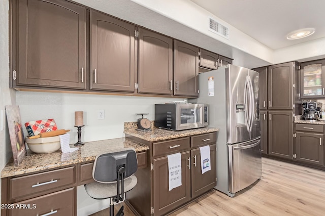 kitchen featuring dark brown cabinetry, built in desk, stainless steel appliances, and light hardwood / wood-style floors