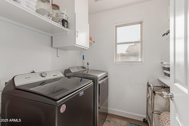 laundry room with hardwood / wood-style flooring, cabinets, and washer and dryer