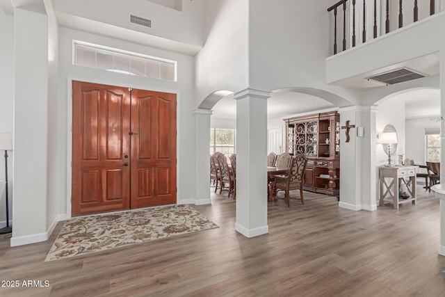 entrance foyer with hardwood / wood-style floors, a high ceiling, and ornate columns