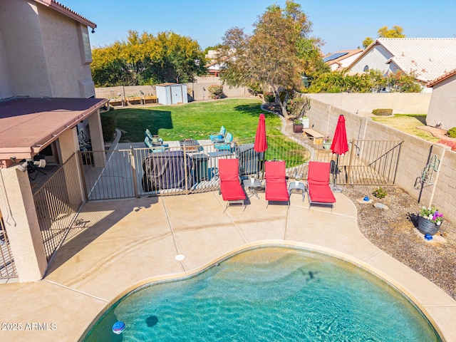 view of swimming pool featuring a shed, a patio area, a lawn, and an outdoor fire pit