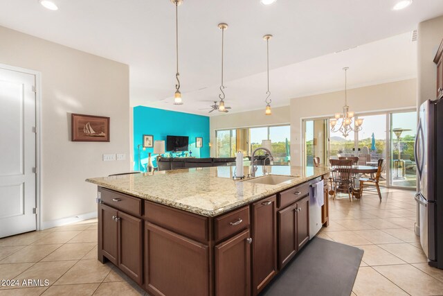 kitchen featuring stainless steel appliances, sink, light stone countertops, an island with sink, and pendant lighting