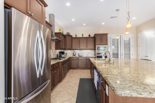 kitchen with stainless steel appliances, sink, wall chimney exhaust hood, pendant lighting, and decorative backsplash