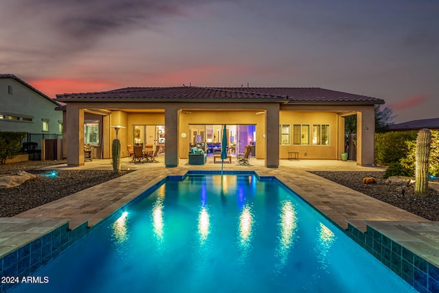 pool at dusk featuring a patio area