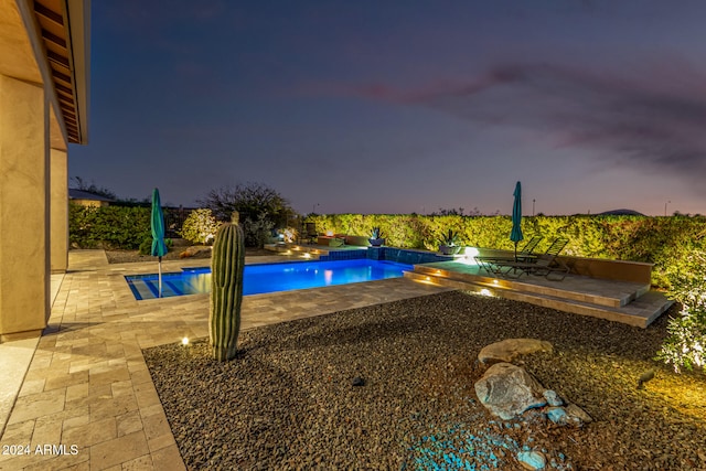 pool at dusk with a jacuzzi and a patio area