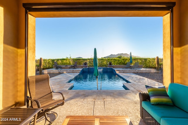 view of pool with a mountain view, pool water feature, an outdoor living space, and a patio area