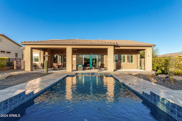 back of property featuring a patio and a fenced in pool