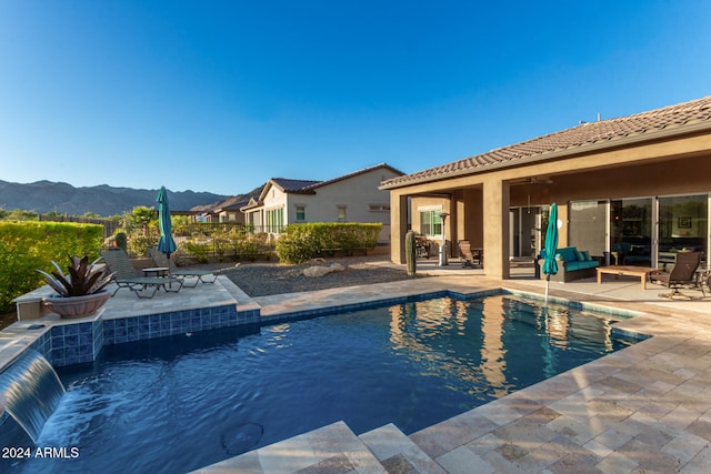 view of swimming pool with a patio area, a mountain view, and pool water feature