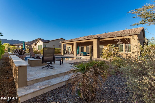 back of house with a mountain view, an outdoor fire pit, and a patio