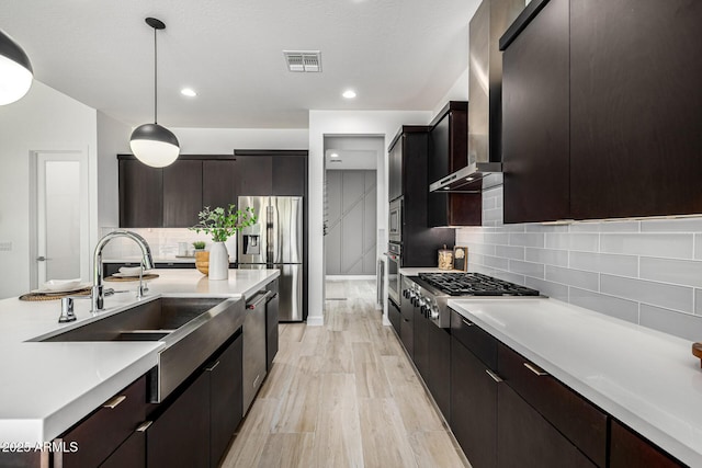 3822 E Canyon Pl, Chandler, AZ 85249 - kitchen featuring stainless steel appliances, wall chimney range hood, hanging light fixtures, light countertops, and backsplash