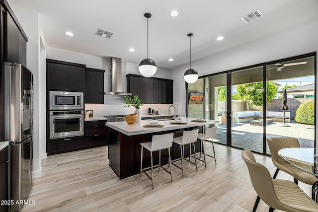 3822 E Canyon Pl, Chandler, AZ 85249 - kitchen with stainless steel appliances, wall chimney range hood, light countertops, a breakfast bar area, and decorative backsplash