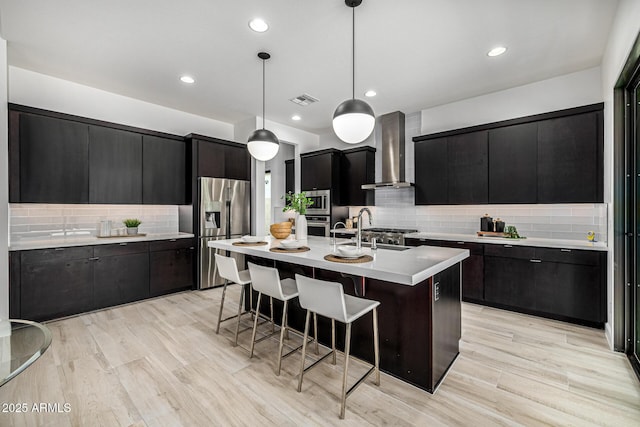 3822 E Canyon Pl, Chandler, AZ 85249 - kitchen with wall chimney exhaust hood, stainless steel appliances, dark cabinets, tasteful backsplash, and light countertops