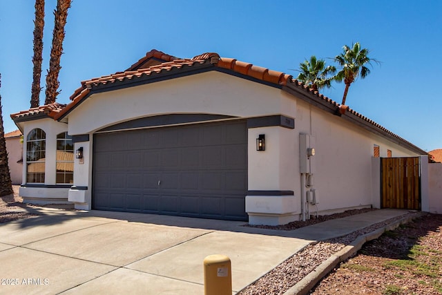 5125 W Wickiup Ln, Glendale, AZ 85308 - view of front of house featuring a tiled roof, a garage, stucco siding, concrete driveway, and a gate