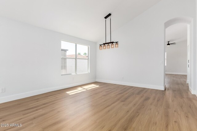5125 W Wickiup Ln, Glendale, AZ 85308 - unfurnished dining area with arched walkways, lofted ceiling, light wood finished floors, and baseboards