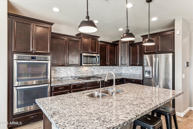 kitchen featuring appliances with stainless steel finishes, a sink, decorative backsplash, and dark brown cabinets