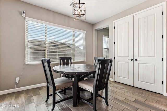 dining space featuring a notable chandelier, baseboards, and wood finished floors