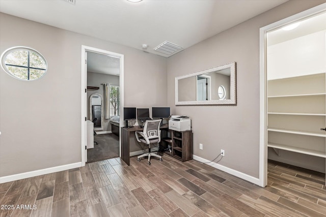 home office with wood tiled floor, a healthy amount of sunlight, and visible vents