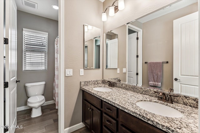 full bath with toilet, visible vents, a sink, and wood finished floors