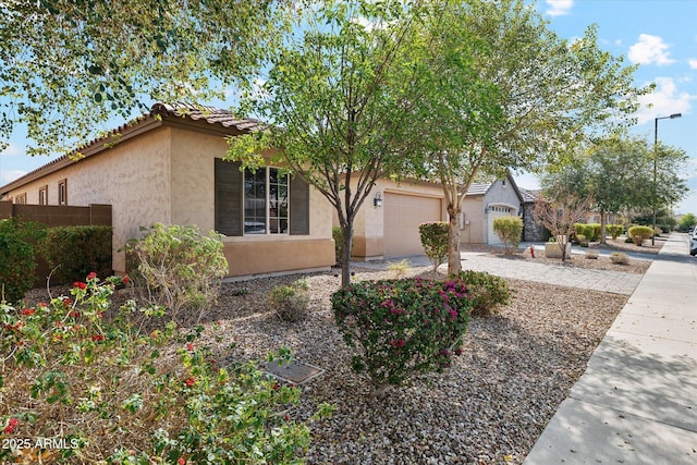 view of front facade with a garage, driveway, a tiled roof, and stucco siding