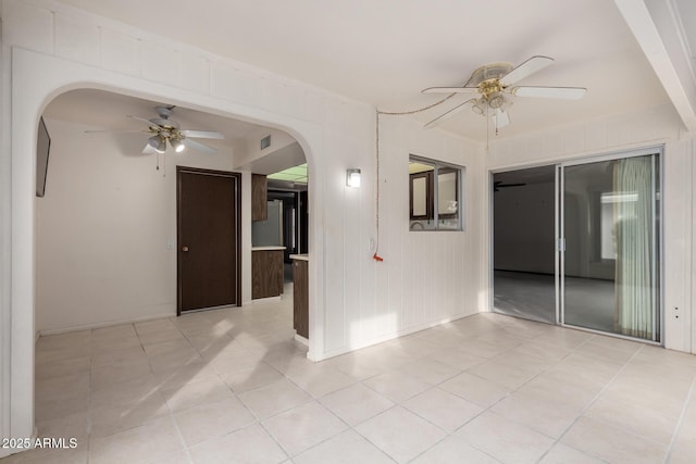 spare room featuring visible vents, arched walkways, light tile patterned flooring, and a ceiling fan