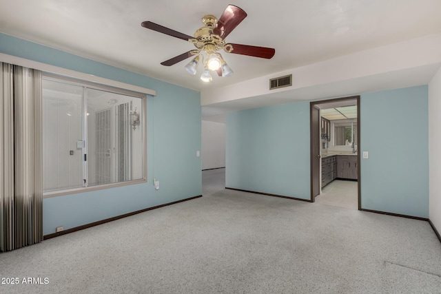 carpeted spare room with visible vents, a ceiling fan, and baseboards