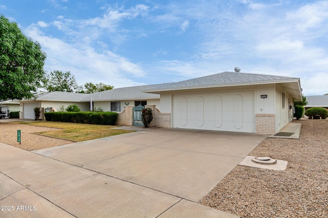 single story home with concrete driveway, a garage, and brick siding