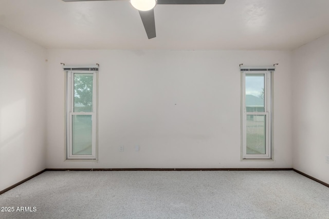 carpeted empty room with a ceiling fan and baseboards