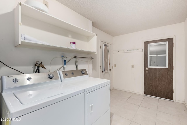 laundry room featuring washer and dryer, laundry area, light tile patterned floors, and a textured ceiling