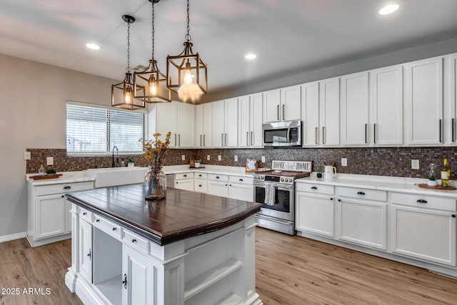 kitchen featuring stainless steel appliances, backsplash, a sink, and light wood-style floors