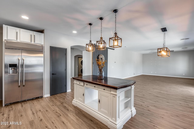 kitchen with built in fridge, butcher block countertops, light wood-style flooring, and white cabinetry