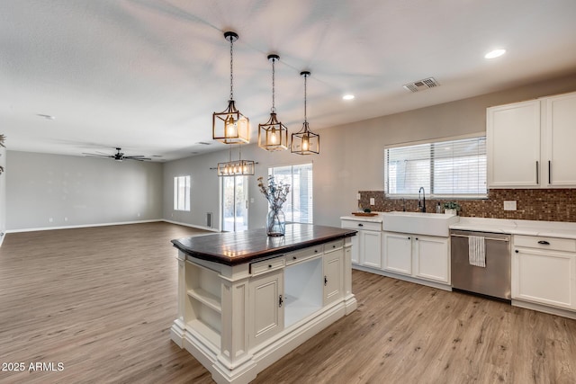 kitchen featuring a sink, visible vents, light wood-style floors, dishwasher, and tasteful backsplash