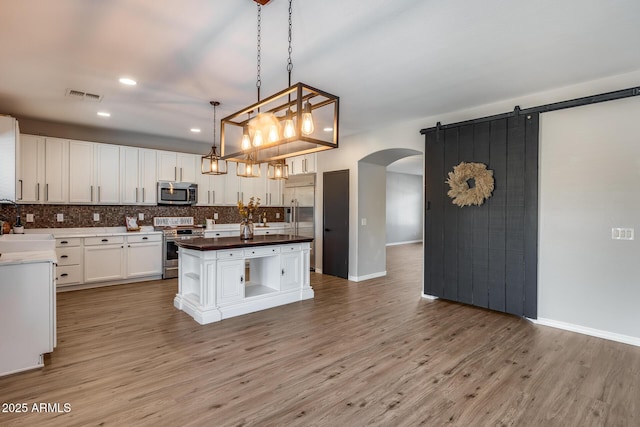 kitchen with stainless steel appliances, tasteful backsplash, visible vents, light wood-style flooring, and white cabinets