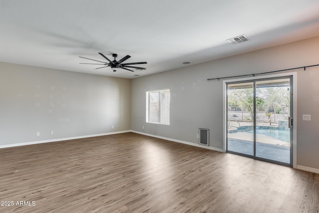 unfurnished room featuring a healthy amount of sunlight, visible vents, and wood finished floors