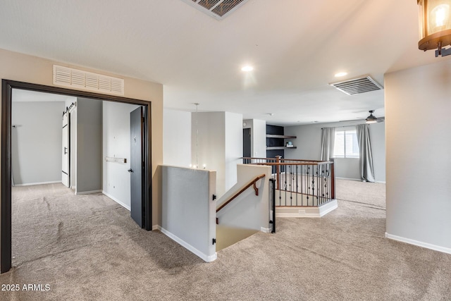 hallway featuring carpet, baseboards, visible vents, and an upstairs landing