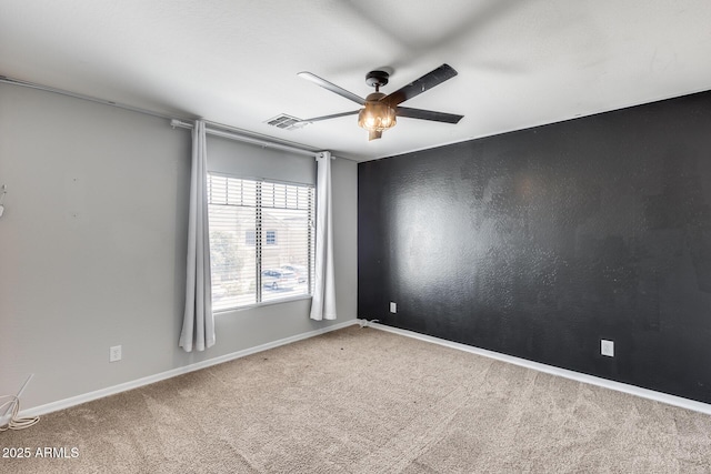 carpeted empty room with baseboards, visible vents, and a ceiling fan