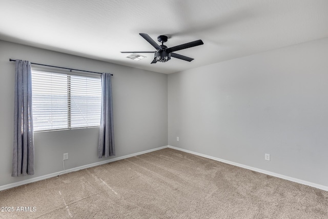 carpeted spare room featuring baseboards, visible vents, and a ceiling fan