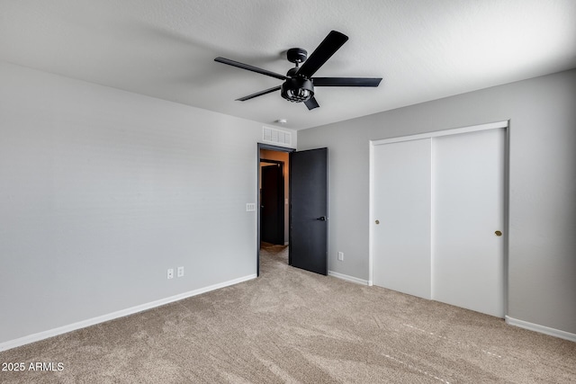 unfurnished bedroom featuring baseboards, visible vents, a ceiling fan, carpet flooring, and a closet