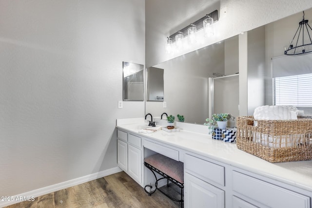 bathroom with a shower with door, wood finished floors, vanity, and baseboards