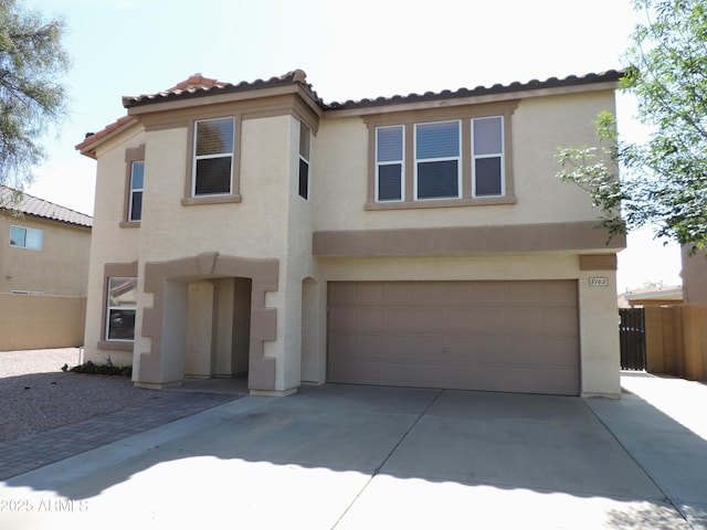 mediterranean / spanish-style home with stucco siding, an attached garage, concrete driveway, and fence