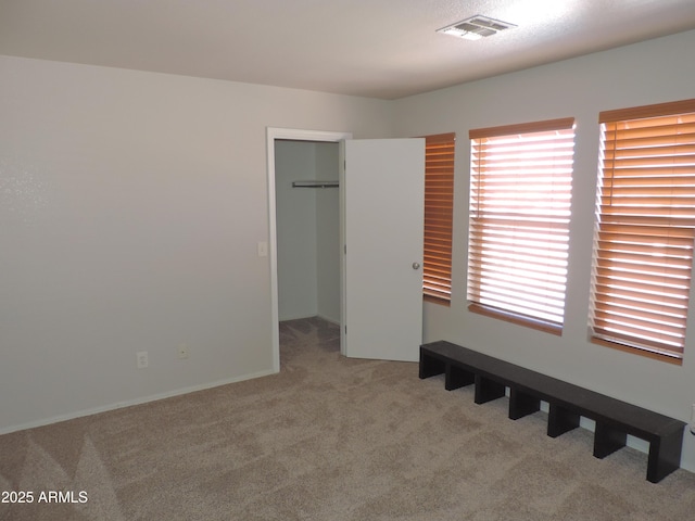 unfurnished bedroom with visible vents, carpet floors, a closet, and a spacious closet