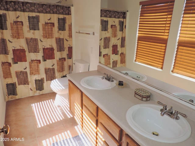 full bathroom featuring a sink, toilet, double vanity, and tile patterned floors