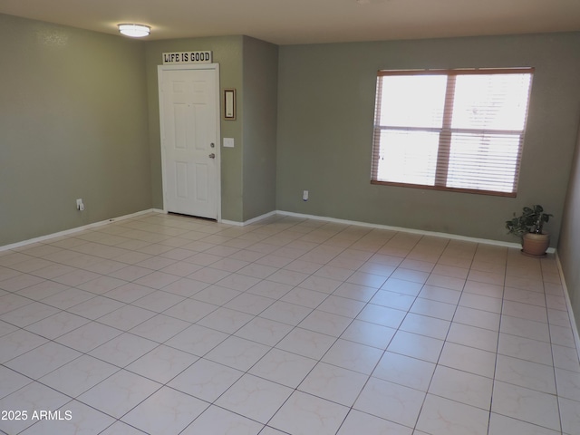 spare room with light tile patterned floors and baseboards