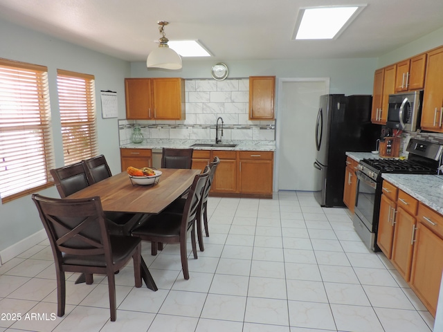 kitchen with a sink, tasteful backsplash, appliances with stainless steel finishes, and brown cabinetry