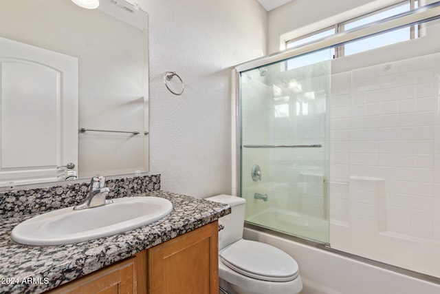 full bathroom featuring vanity, toilet, and shower / bath combination with glass door