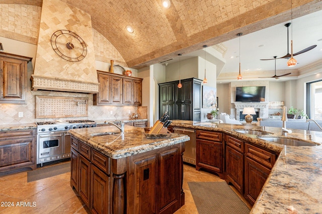 kitchen with pendant lighting, an island with sink, sink, stainless steel appliances, and light stone countertops